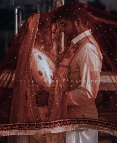 a bride and groom kissing under an umbrella