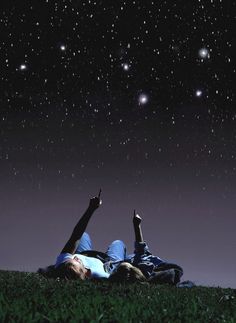 two people laying in the grass under a night sky with stars and planets above them