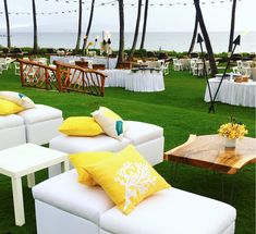 white couches with yellow pillows are set up on the grass near tables and chairs