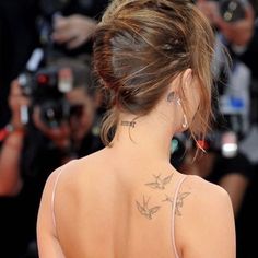 the back of a woman's neck with tattoos on her left shoulder and right arm