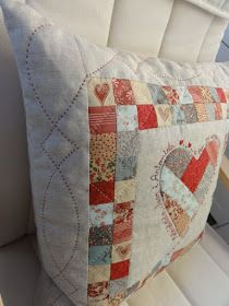 a close up of a pillow on a couch with white cushions and quilted hearts