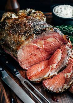 sliced roasted prime rib steak on cutting board with knife and rosemary sprigs