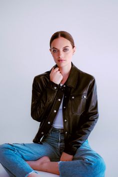 a woman is sitting on the floor with her hand under her chin