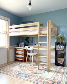 a loft bed with desk underneath it in a room that has blue walls and hardwood floors