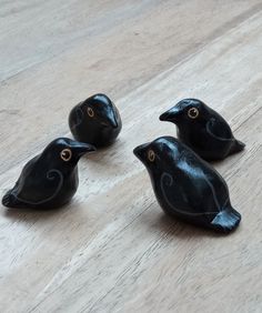 three black birds sitting on top of a wooden floor