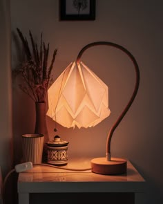 a white lamp sitting on top of a table next to a vase and potted plant