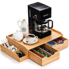 a coffee maker and some cups on a tray with drawers underneath it that hold various items