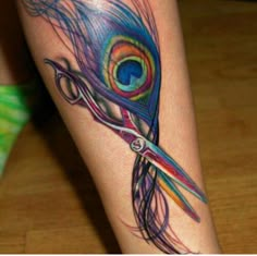 a woman's leg with a tattoo on it and scissors in the shape of a peacock