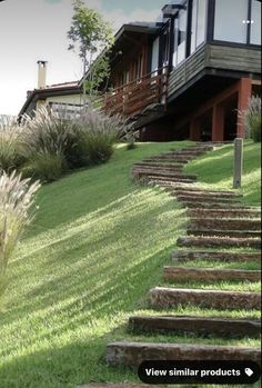 there is a house on the hill with stairs leading up to it and grass in front