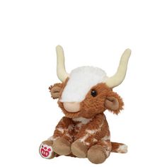 a brown and white stuffed cow with horns on it's head sitting in front of a white background