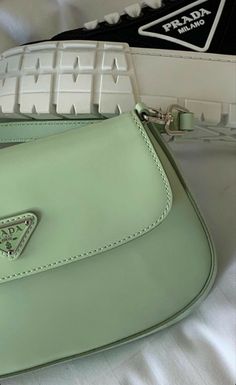 a green purse sitting on top of a white bed