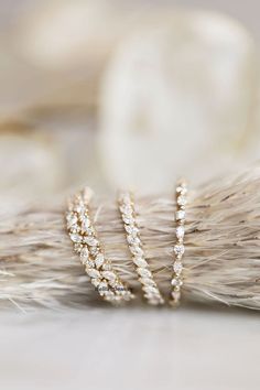 three gold and diamond rings sitting on top of feathers