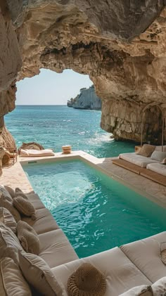 an outdoor swimming pool with couches and tables in front of it, next to the ocean