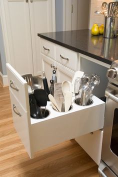 an open drawer in the middle of a kitchen with utensils and spoons