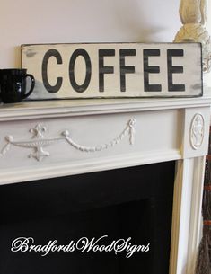 a coffee sign sitting on top of a white fireplace mantel next to a cup