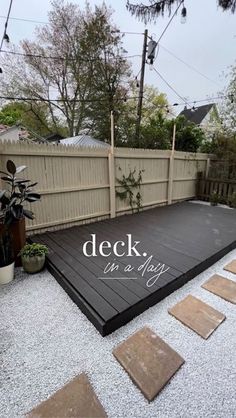 a deck in a backyard with stepping stones on the ground and plants next to it