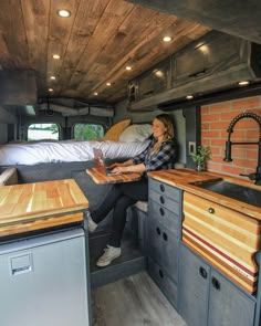 a woman sitting in the back of a camper looking at her laptop while reading