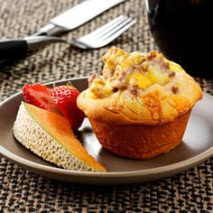 a muffin on a plate with fruit next to it