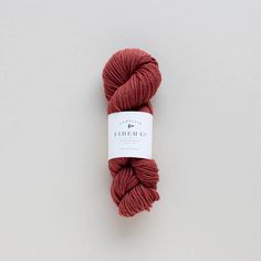 a skein of red yarn sitting on top of a white surface with a tag