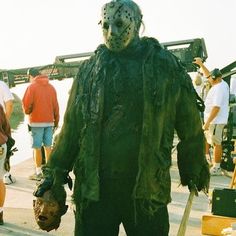 a man in a costume standing on the side of a road with people behind him