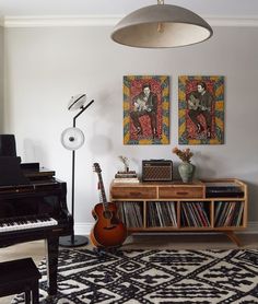 a living room filled with furniture and a piano in front of two paintings on the wall