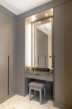 a vanity with a stool and mirror in a room that has light on the ceiling