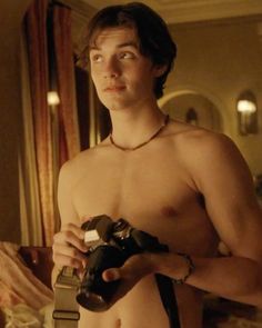 a shirtless man holding a camera in his hand