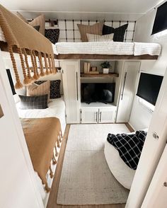 two beds in a small room with white walls and wood flooring on the bottom level