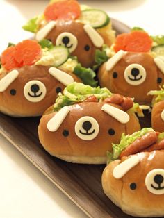 some very cute looking food items on a wooden tray with carrots and cucumbers