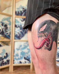 a man with a tattoo on his leg that has a large dinosaur in it's mouth