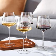 three wine glasses sitting on top of a wooden tray