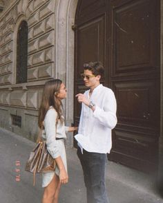 a man standing next to a woman in front of a building