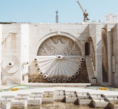 a large building with an intricate design on the front and side wall, surrounded by concrete blocks