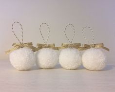 three white pom - poms with gold bows are lined up in a row