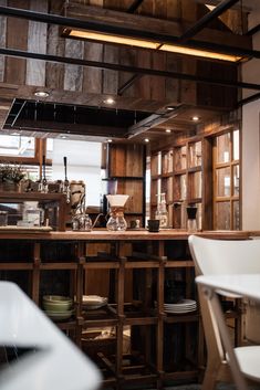 a kitchen filled with lots of wooden shelves next to a table and chairs in front of a window