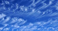 the blue sky is filled with clouds and white wispy lines in the foreground