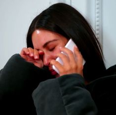 a woman talking on a cell phone while holding her hand to her face