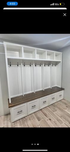 an empty room with white cabinets and wooden benches on the wall, next to a wood floor