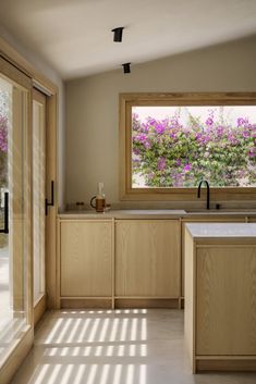 an empty kitchen with wooden cabinets and flowers in the window sill on the wall