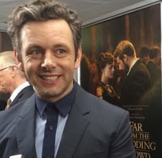 a man in a suit standing next to a movie poster