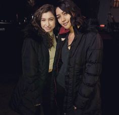 two women standing next to each other in the dark