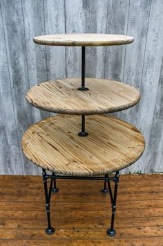 three tiered wooden table sitting on top of a hard wood floor next to a wall