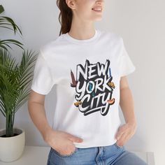 This T-Shirt featuring a design of New York City exudes a modern and urban vibe, perfect for city lovers and travelers. It is a versatile piece that can be worn casually or semi-formally, making it suitable for various occasions and settings. The lightweight cotton fabric is breathable and easy to layer, ideal for active and leisure wear. The unisex fit and classic crew neckline make it a staple in any wardrobe. Product features - 100% Airlume combed and ring-spun cotton - Retail fit for casual and semi-formal settings - Variety of fabric blends for different color options - Tear-away label for minimal skin irritations - Manufactured with sustainable and ethical practices by Bella+Canvas Care instructions - Machine wash: cold (max 30C or 90F) - Non-chlorine: bleach as needed - Tumble dry: City Skyline Tshirt, Semi Formal, Leisure Wear, Short Sleeve Shirt, New York City, Cotton Fabric, New York, Bathing Beauties, Tops & Tees