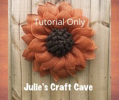 an orange sunflower with the words julia's craft cave written below it on a wooden fence