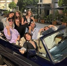 a group of people sitting in the back of a car waving and posing for a photo