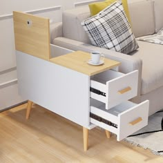 a white coffee table with two drawers and a cup on it next to a couch