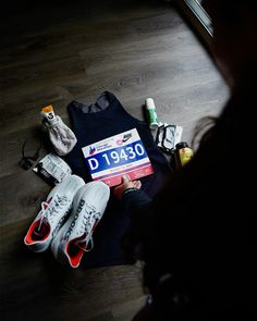 a person sitting on the floor with some shoes and other items around them, including a t - shirt that says d190