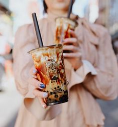 a woman holding two drinks in her hands