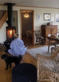 a woman sitting on the floor in front of a fire place with a black dog