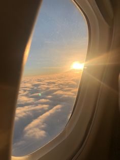 the sun is shining through the window of an airplane as it flies above the clouds